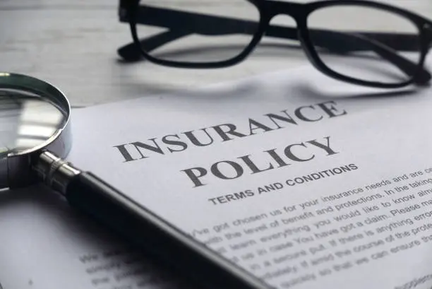 Selective focus of a magnifying glass on a paper on insurance policy || insurance companies in Africa